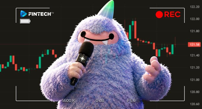 A furry purple and blue monster character holding a microphone in front of a fintech trading chart, labeled 'FINTECH TV' with a 'REC' indicator.