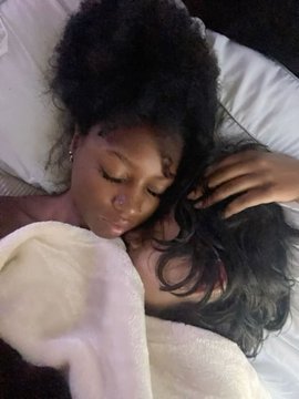 A close-up selfie of a young woman resting her head against another person with dark curly hair, sharing an intimate moment under white bedding, with a soft cream-colored blanket visible. The caption "me and my sp core ::" reflects the affectionate, soulmate-like closeness between the two individuals in the image.