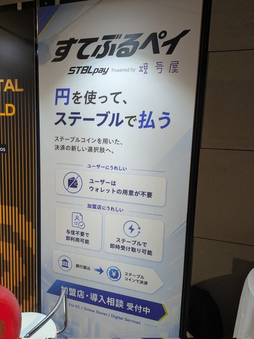 A promotional banner for "STBL Pay" (すてぷるペイ), a crypto payment service powered by 暗号資産 (crypto asset) platform 兮屋, advertising the use of Stablecoins for seamless payments. The sign highlights benefits for users (no wallet needed) and merchants (ID-free sign-up and instant stablecoin receipt), with franchise inquiries currently open for EC, online stores, and digital services.