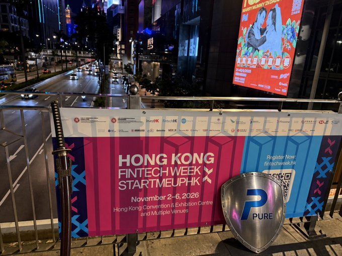 A nighttime photo from a pedestrian bridge overlooking a Hong Kong street, featuring banners for 'Hong Kong FinTech Week x StartmeupHK' (November 2-6, 2026) and a 'Pure' group shield logo.