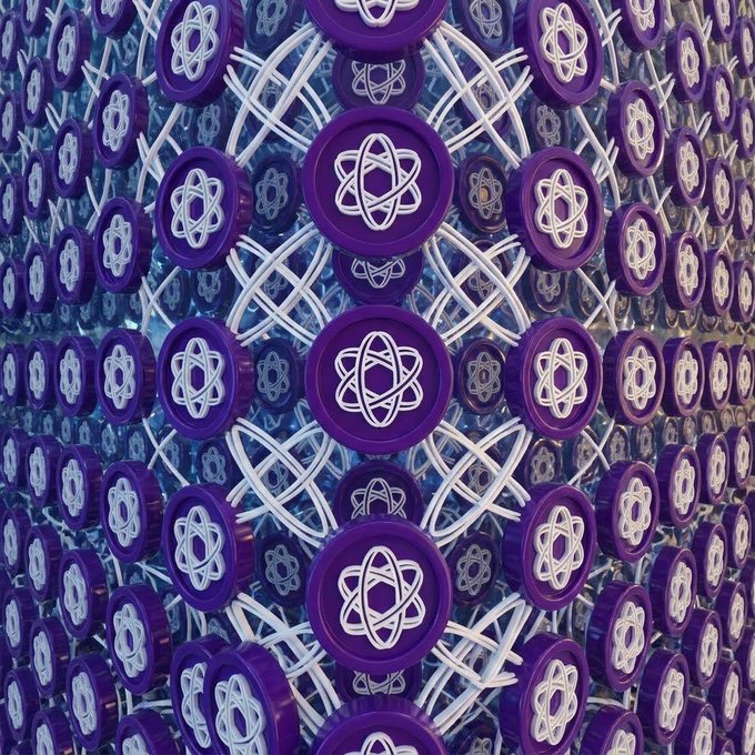 A repeating pattern of purple circular tokens featuring white atomic/nuclear symbols arranged on a reflective curved surface.