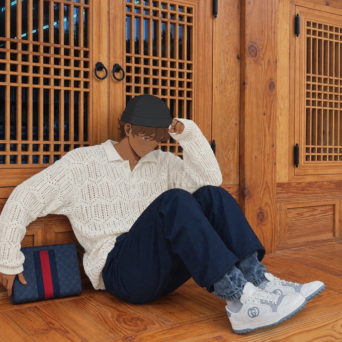 A young man in a white knit sweater, navy pants, and a black cap sits on a wooden floor against traditional wooden lattice doors, holding a Gucci-patterned clutch, embodying the stylish, on-brand aesthetic tied to the post's mention of NFTs evolving into gateways for attention, exclusive launches, and utility-driven ownership.