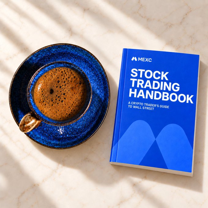 A blue MEXC "Stock Trading Handbook: A Crypto Trader's Guide to Wall Street" rests on a marble surface beside a cup of espresso in a vibrant blue ceramic saucer, bathed in warm sunlight—perfectly capturing the post's theme of a relaxed morning reading session before diving into TradFi markets.