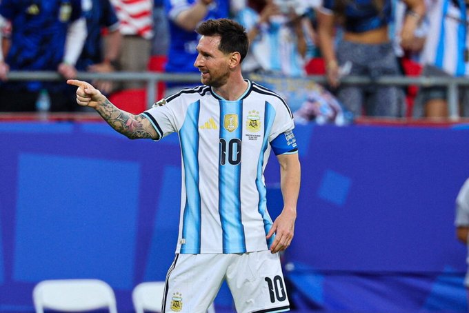 The image features a soccer player wearing a blue and white striped jersey with the number 10, standing on a field and pointing towards something off-camera. The background of the photo shows several people watching the game from behind a barrier or fence. There is also an element in the image that reads "Form is temporary. Class is permanent. That'S Messi That'S GOAT". This phrase seems to be related to the soccer player's performance and the post discussing his skills, suggesting that the image might have been taken during a game or event where he was playing.