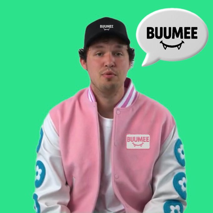 A man wearing a black "BUUMEE" cap and a pink and white varsity jacket with a "BUUMEE" patch stands against a green background, accompanied by a speech bubble reading "BUUMEE" with a smiley mouth design.