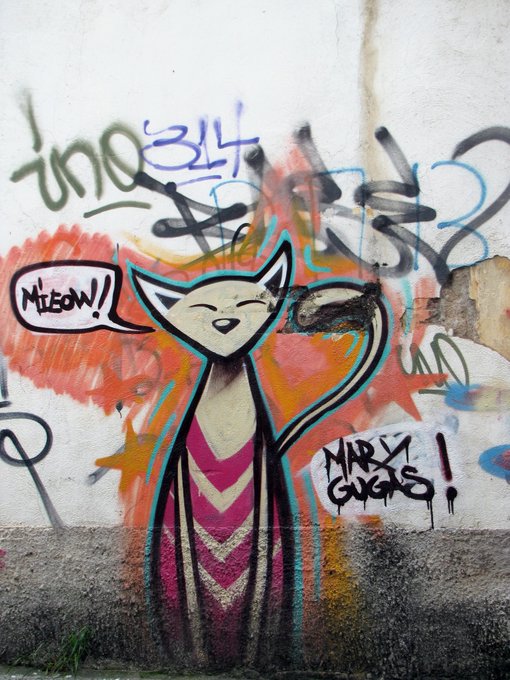 Street art on a wall depicts a cartoon cat saying 'MEOW!' in a speech bubble, with the signature 'MARTY GUGGS' visible.