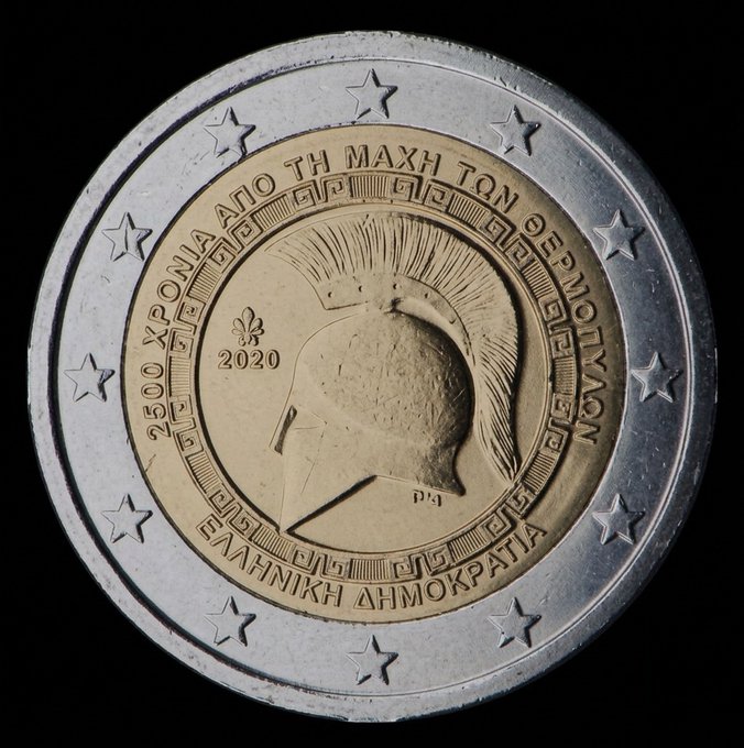 A close-up of a Greek 2 Euro commemorative coin from 2020 celebrating '2500 Years Since the Battle of Thermopylae,' featuring a Spartan warrior helmet design.
