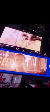 A person's portrait art is displayed on a large illuminated billboard in Times Square during NFT.NYC 2026, with "ZLEY" and "orders" partially visible in the bright nighttime scene.