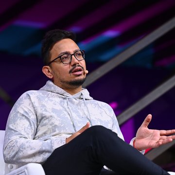 A man with glasses and a beard, wearing a patterned hoodie, speaks while gesturing with his hands at what appears to be a conference or panel discussion. The image accompanies news about Polygon Foundation CEO Sandeep Nailwal's announcement regarding the permanent burning of 100 million POL tokens.