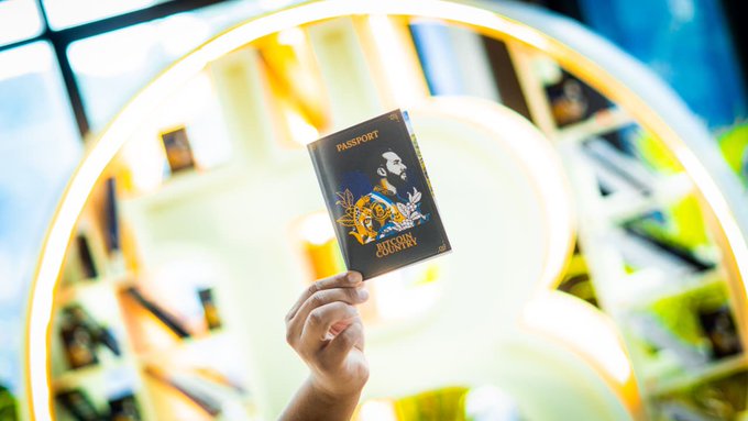 The image features a person holding up an open book, which appears to be a passport or travel document from El Salvador. The background of the image shows a large lighted circle with various items displayed within it, including books and other objects. The text in the image suggests that El Salvador is known for Bitcoin, and there are several books related to Bitcoin on display.