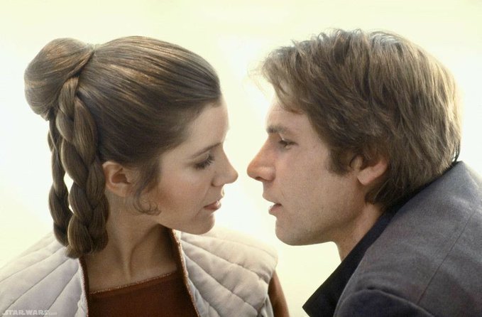 Princess Leia with braided hair bun and Han Solo face each other closely in a close-up shot.