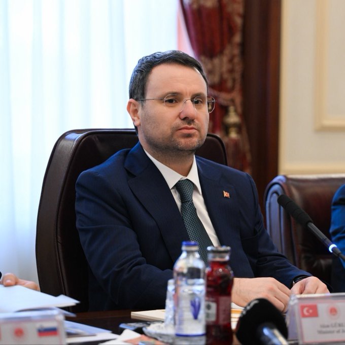 Justice Minister Gürlek, seated at a conference table with a nameplate reading "Minister of Ju[stice]" alongside a Turkish flag, appears to be addressing the press. His statement reflects the image's formal setting, announcing the seizure of bank accounts, safe deposit boxes, and crypto assets belonging to 818 suspects linked to four criminal organizations.