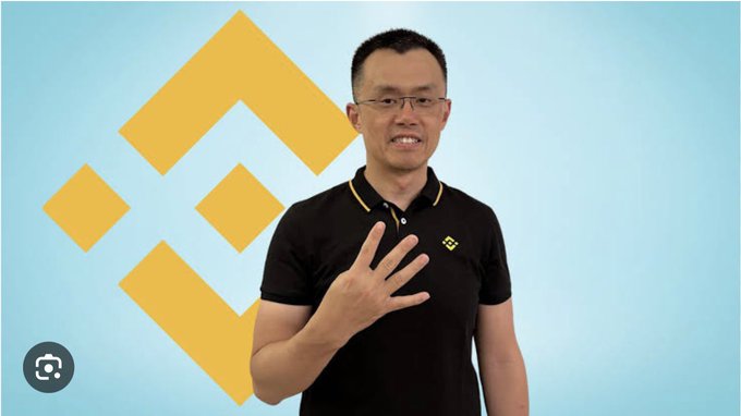 A man stands in front of a light blue background with a large yellow Binance (BNB) logo, smiling and holding up four fingers while wearing a black polo shirt featuring the Binance logo. The image relates to the post as it shows what appears to be Changpeng Zhao (CZ), whose profile picture change reportedly boosted the $MUBARAK meme coin on BNB Chain.