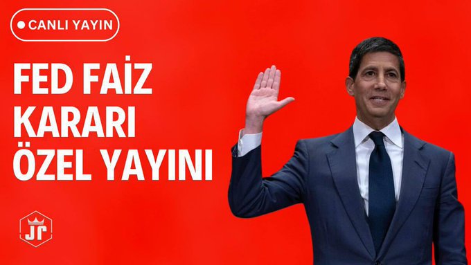 A man in a navy suit raises his hand against a red background that displays the Turkish text "CANLI YAYIN" (Live Broadcast), "FED FAİZ KARARI ÖZEL YAYINI" (Special Broadcast of the FED Interest Rate Decision), and a "Jr" logo, promoting a live stream covering the Federal Reserve interest rate announcement.