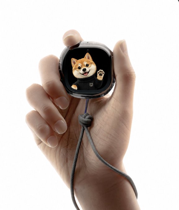 A hand holds a small square smartwatch displaying a Shiba Inu dog character waving, attached to a gray wrist strap.