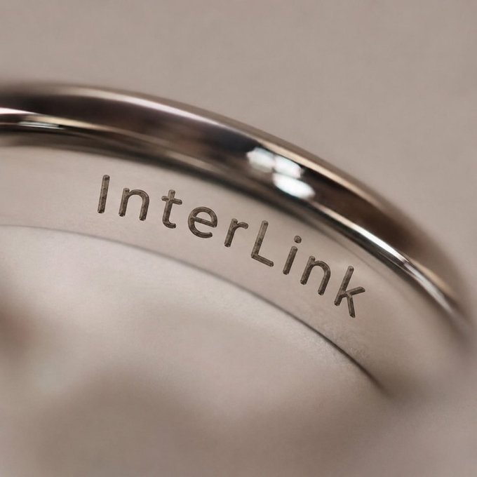 A close-up macro photograph shows a silver ring engraved with the word 'InterLink'.
