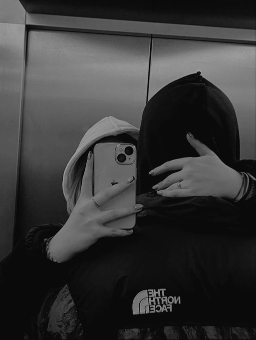 A black-and-white mirror selfie taken in an elevator shows a person wearing a The North Face jacket, holding an iPhone (with a ring visible on their finger) to obscure their face. The image visually reinforces the post's message about persistence and community, with the prominent North Face branding echoing the "keep showing up" theme of building Web3 adoption.