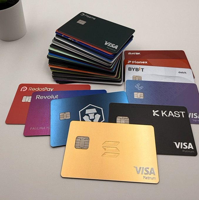 A stack and spread of various branded debit/credit cards including Plaid, Krak, Pionex, BYBIT, RedotPay, Revolut, Crypto.com, and KAST, most featuring a VISA Platinum chip.