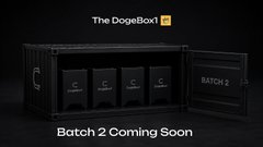 A promotional image for 'The DogeBox 2' showing a black box containing four items, with text indicating 'Batch 2 Coming Soon'.