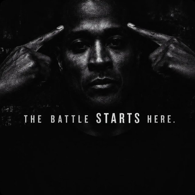 A dark, moody portrait of a man pointing to his temples with the motivational text 'THE BATTLE STARTS HERE.' displayed at the bottom.