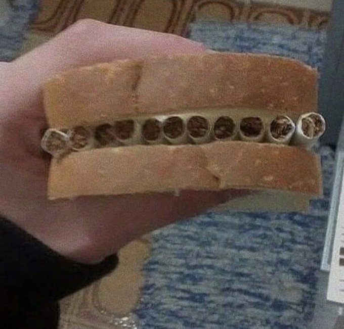 A hand holding a slice of bread with a chocolate-filled wafer cookie (resembling a Kinder Bueno) placed in between the two halves.