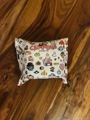 A small zippered pouch decorated with Japanese food illustrations rests on a wooden surface, featuring red Japanese text reading 'カプセル' (capsule) at the top.