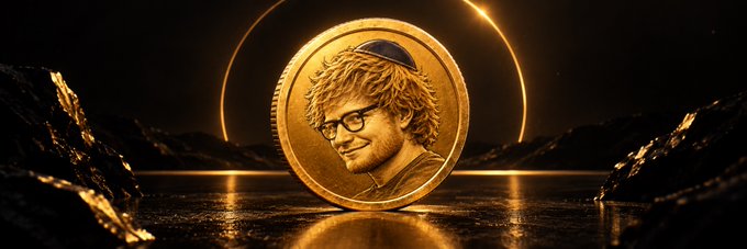 A golden commemorative-style coin featuring a portrait of a man with curly blonde hair, glasses, and a beard—stylized to resemble Ed Sheeran with a Jewish identity motif—rests upright on a reflective dark surface, framed by rocky terrain and a glowing solar eclipse in the background, visually representing the meme ticker "$JEW."