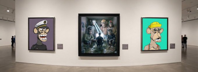 A gallery exhibition displaying three NFT-style artworks of cartoonish monkey/chimp characters in uniform attire alongside a central framed scene with characters in a mystical setting.