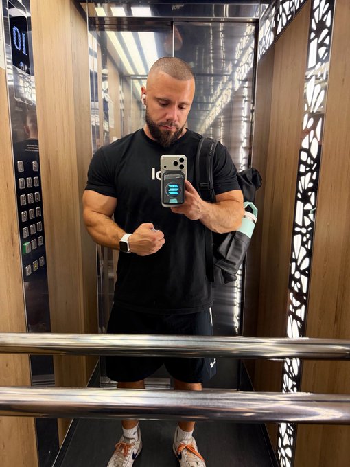 A muscular man takes a mirror selfie in an elevator while flexing his arm, wearing a black t-shirt, earbuds, and carrying a gym bag. The post's bullish sentiment on Solana mirrors his confident, "pumped up" pose, visually representing strength and positive momentum in the crypto market.