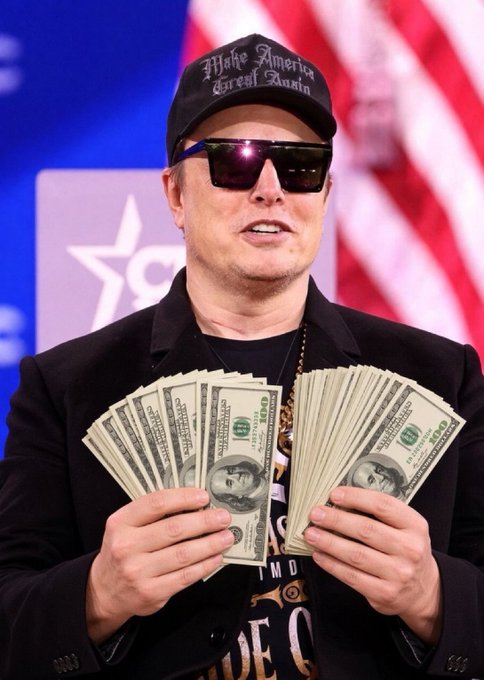 A man wearing sunglasses and a black 'Make America Great Again' cap, holding up two fans of US $100 bills in front of an American flag backdrop.
