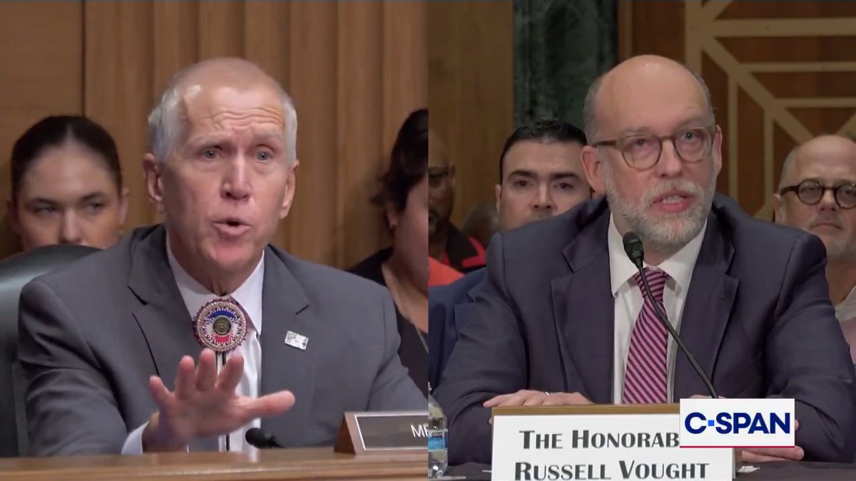 Two men are seated at a Senate hearing, with the man on the right identified by a nameplate reading "THE HONORABLE RUSSELL VOUGHT" speaking into a microphone, as the C-SPAN logo appears in the corner. The image captures a moment from Vought's testimony, which the accompanying post references to highlight the administration's inability to cite specific DOGE cost-saving achievements.
