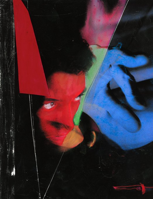 An artistic, abstract image featuring a face painted with red, green, and blue colors against a black background, overlaid with geometric shapes.