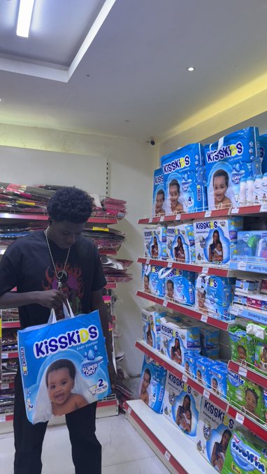 A young man stands in a baby products aisle examining a "KISSKIS" diapers package featuring "SUPER DRY" and size "2" labels, with shelves fully stocked behind him. The post "i don fvck up" humorously implies his error of accidentally purchasing adult diapers or shopping in the wrong section.