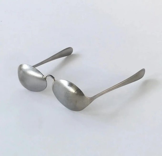 A pair of minimalist silver-toned oval sunglasses with thin metal temples, photographed against a plain white background.