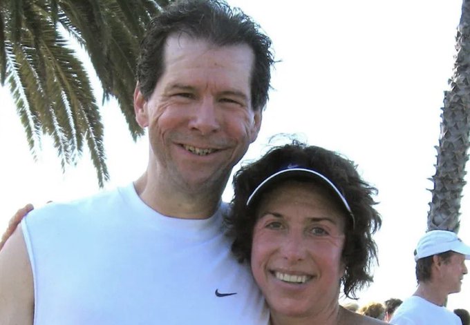 A man and woman pose together smiling outdoors near palm trees, with the man wearing a white sleeveless Nike shirt and the woman wearing a white headband, in what appears to be a sunlit beachside or coastal setting. The image likely depicts Hal Finney alongside his wife, commemorating the 12-year anniversary of his cryopreservation following his death from ALS complications.