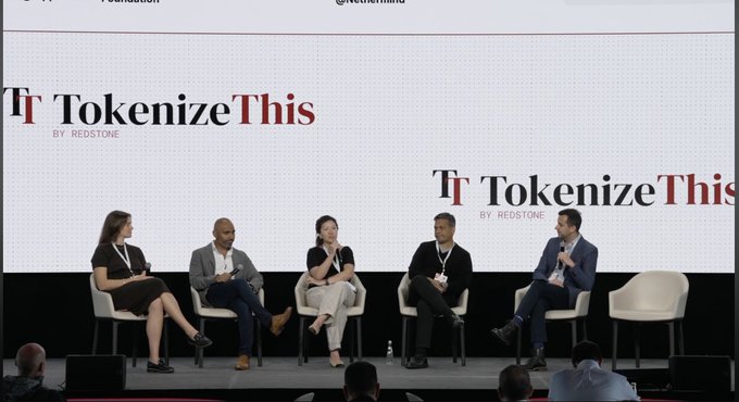 A panel discussion on stage at the "TokenizeThis by Redstone" event features five speakers seated in a row, with the backdrop displaying the event's branding. The image aligns with the post's theme of institutional crypto adoption and multi-network interoperability, showcasing Ripple and StellarOrg representatives sharing the stage to discuss how blockchain networks can collaborate.