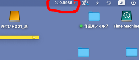 A computer desktop screenshot with a red circle highlighting the value '0.9986' in the top menu bar, with Japanese folder labels including '外付け HDD1_新', '作業用フォルダ', and a 'Time Machine' icon.