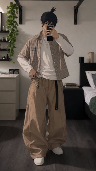 A mirror selfie of a person with dark hair in a topknot, wearing a checkered overshirt, white t-shirt, and baggy tan pants with a wallet chain, standing in a bedroom.