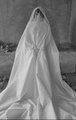 A black and white image of a figure draped in a long white sheet, resembling a classic ghost costume.