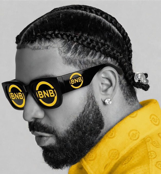 A side profile portrait of a man with braided hair and a beard, wearing black sunglasses with yellow "BNB" logos (Binance coin), a diamond earring, and a yellow patterned shirt, presented in a stylized black-and-white with yellow accents.