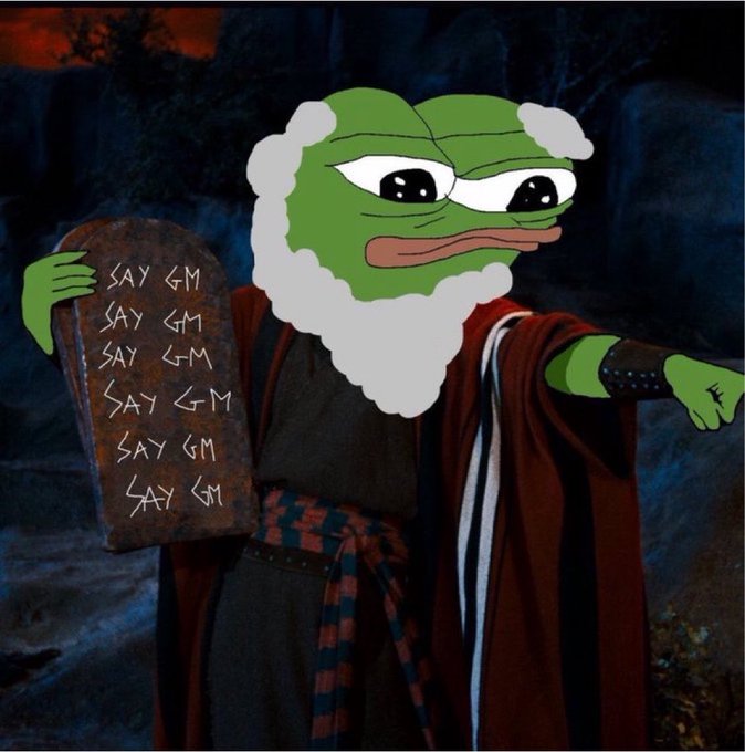 A meme image of a green Pepe frog edited with a white beard and robes to resemble Moses, holding stone tablets inscribed with "SAY GM."