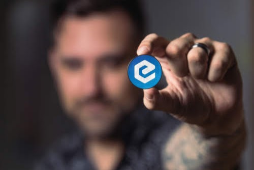 The image features a man holding up a blue coin with the number "E" on it, which appears to be worth $XEC. The caption below the coin reads "It'S #eCash my favorite coin." This suggests that the coin is valuable and possibly related to cryptocurrency or digital currency.