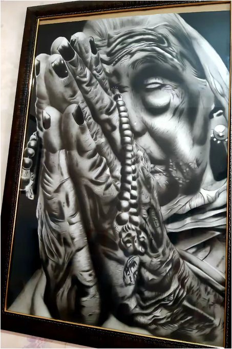 A framed, highly detailed black-and-white drawing portrays a weathered face and hand holding a beaded necklace, rendered with striking realism.