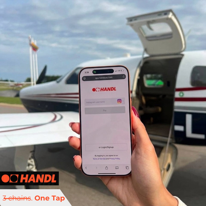 A hand with red nail polish holding up a smartphone displaying the 'HANDL' login page (app.handlr.com) with an Instagram username field, set against the background of a small airplane with an open cargo door on a tarmac.