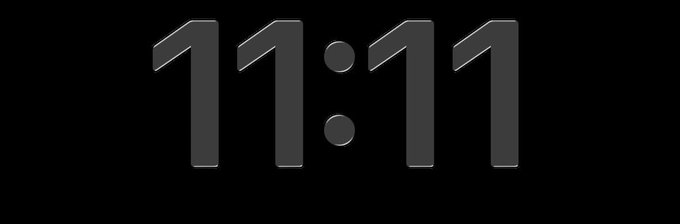 A digital clock display showing the time "11:11" in silver/grey 3D-style numbers on a black background.