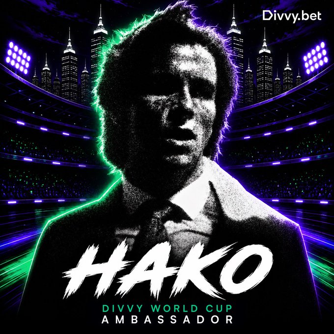 The image features a poster for the Divvy World Cup, which has a man's face prominently displayed with the text "Hako" written below his head. The background of the poster shows a city skyline at night, adding an urban touch to the overall design. The poster also includes a link to the Divvy Bet website and mentions that there is no need for a registration or any other form of payment to participate in the World Cup.