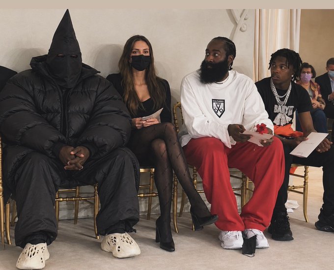 This image appears to show Kanye West (in his distinctive masked outfit), his wife Bianca Censori, and what looks like James Harden seated together in the front row of a fashion show. The accompanying post mentions cryptocurrencies "Monero, Z Cash, Bitcoin, Solana," but the image itself doesn't display any text, numbers, or tickers related to these currencies—it's simply a photo of celebrity attendees at what appears to be a fashion event.

A concise caption: Kanye West (in a black mask and puffer jacket), Bianca Censori, and James Harden sit front row at a fashion show, though no cryptocurrency-related text is visible in the image.