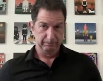 The image features a man wearing a black shirt standing against a wall with several paintings hanging above him. The man appears to be looking directly at the camera, engaging the viewer with his presence. The text "if you hold $HOOD go buy some $TIBBIR thesis: @mickymalka" is also present in the image, which could potentially be related to a discussion or review of one of the paintings on display.