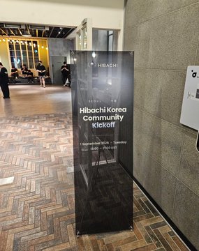 A black standing sign for the 'Hibachi Korea Community Kickoff' event, displaying the date 'September 2026' and time '20:00 - 21:00 (UTC-7)' in a modern lobby area.