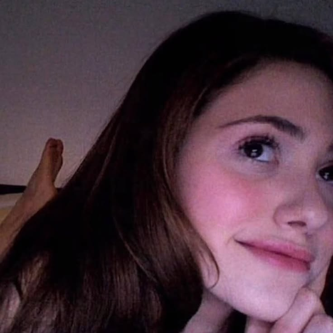 A young woman with long brown hair rests her chin on her hand, offering a subtle, knowing smile toward the camera. The relaxed, intimate selfie pairs with the post's tone of casual confidence, mirroring the laid-back excitement of jumping into @Overtime_io's $5k "Casino Rush I" volume-based pool event.